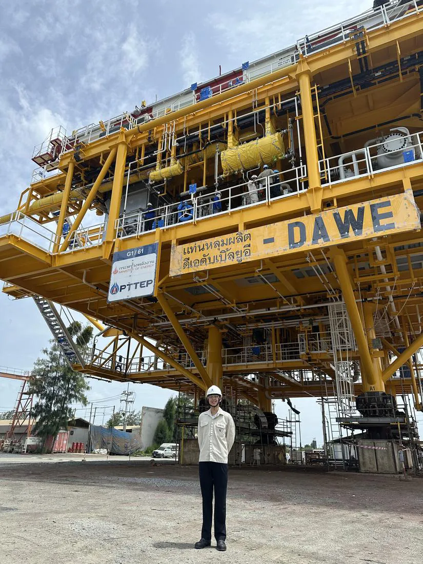 Sun in a hard hat in front of the DAWE wellhead platform at the PTTEP yard