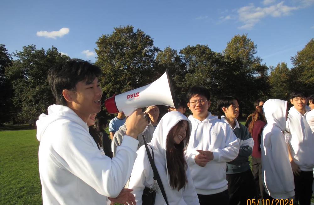 Sun leading Imperial Thai Society members with a megaphone at an outdoor event